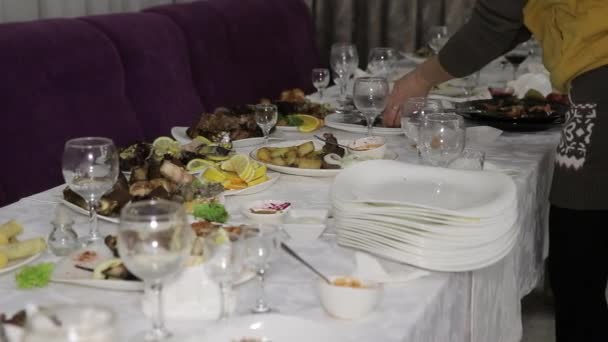 Die Kellnerin sammelt die schmutzigen Teller mit den Essensresten in einem Haufen ein. Tische nach einem Urlaub oder Bankett. - Filmmaterial, Video