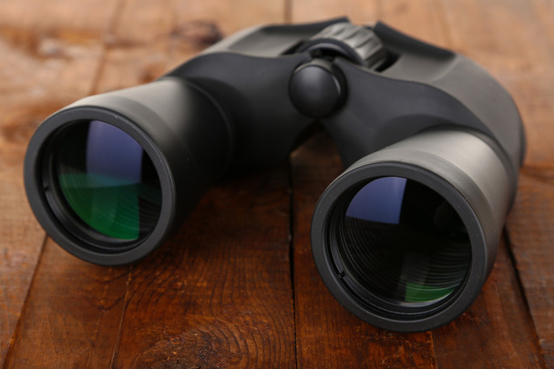 Black modern binoculars on wooden background - Photo, Image