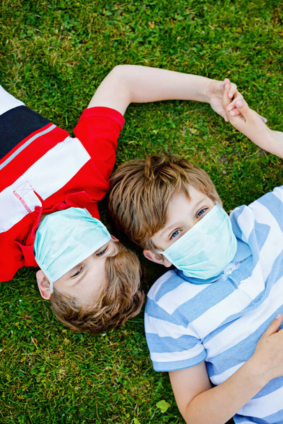 Dwoje chłopców w maskach medycznych jako ochrona przed pandemią koronawirusową. Dzieci, urocze rodzeństwo i najlepsi przyjaciele używający sprzętu ochronnego do walki z covid 19. - Zdjęcie, obraz