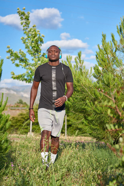 African athlete listening to music while warming up the muscles while taking a walk. - Valokuva, kuva