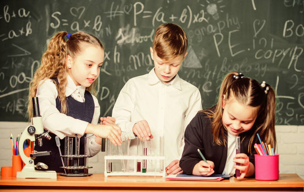 Formal education. Girls and boy student conduct school experiment with liquids. School laboratory. Group school pupils study chemical liquids. School chemistry lesson. Test tubes with substances - Foto, immagini