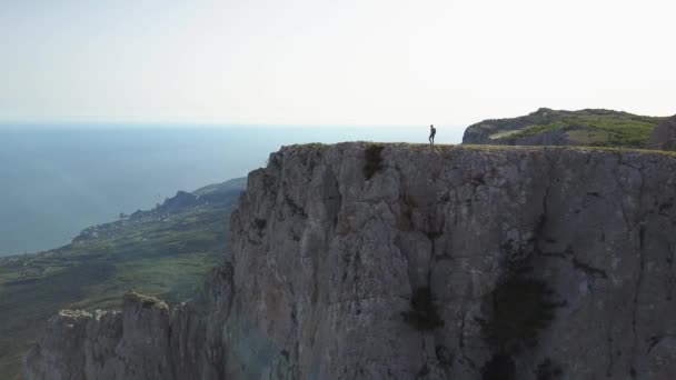 Hermoso paisaje de la altura de un turista en una caminata caminando en tiempo soleado a lo largo del borde de la montaña más alta de Crimea - Ai-Petri, Yalta, Ucrania. Hombre atlético camina por el precipicio
. - Metraje, vídeo