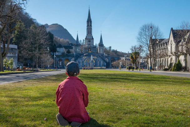 un joven con la catedral-santuario de Lourdes (Francia
) - Foto, Imagen