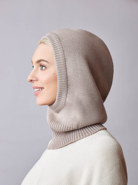 European Muslim woman with a blonde hair in a bonnet hood dressed on her head. Beautiful girl in sweater with soft skin, natural cosmetics - Foto, Bild