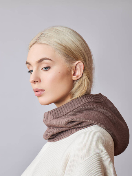 European Muslim woman with a blonde hair in a bonnet hood dressed on her head. Beautiful girl in sweater with soft skin, natural cosmetics - Foto, Bild