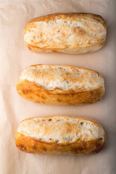 Rouleaux de pain français en rangée sur papier cuisson. - Photo, image