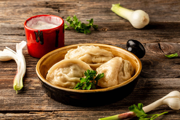 Uzbek prepared boiled Manti or manty dumplings in a traditional bowl on wooden table. banner menu recipe place for text. - 写真・画像