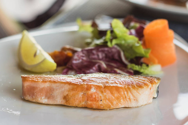 Salmon grilled on the white plate, serve with vegetables and lemon. - Photo, Image