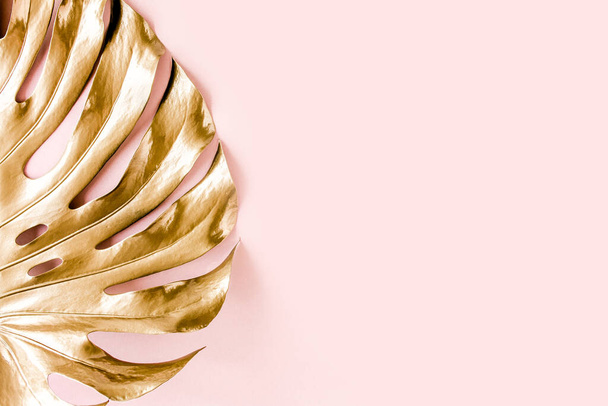 Gold tropical palm leaves Monstera on pink background. Flat lay, top view minimal concept. - 写真・画像