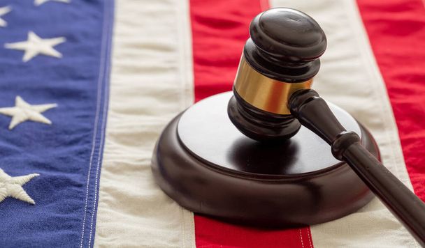 Судья или аукционный молоток на фоне флага Соединенных Штатов Америки. Концепция правосудия и права в США
 - Фото, изображение