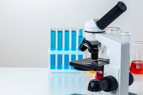Close up of laboratory microscope with set of test tubes with blue liquid - Foto, Bild