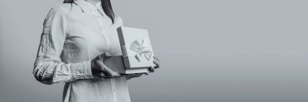 Chica joven abre una caja de regalo. La cara de la chica no es visible. Imagen en blanco y negro
. - Foto, Imagen