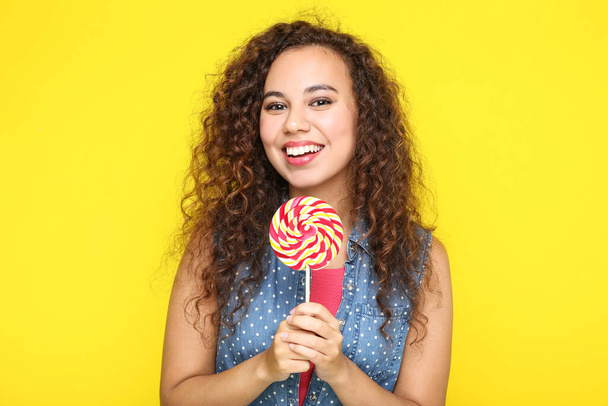 Young american girl with lollipop on yellow background - Zdjęcie, obraz