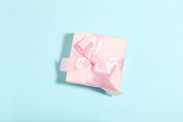 Gift box with ribbon bow on blue background. Minimalism concept - Foto, Imagem