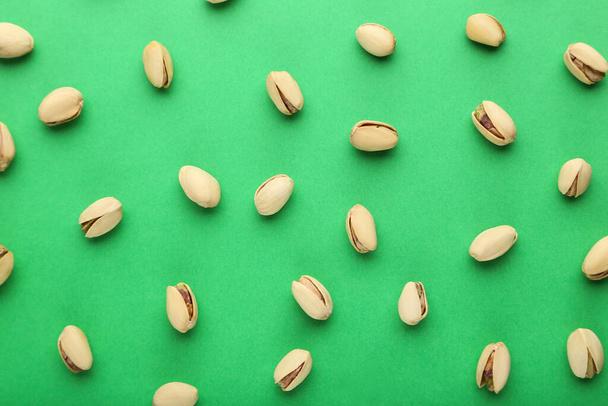 Tasty pistachios on green background - Foto, afbeelding