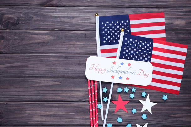 Text Happy Independence Day with flags, red straws and paper stars on wooden background - Photo, image