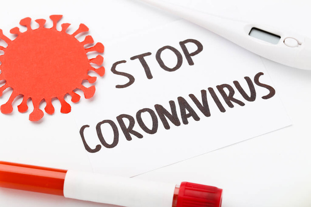 Text Stop Coronovirus with thermometer and test tube on white background - Fotografie, Obrázek