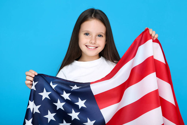 Young girl holding american flag on blue background - 写真・画像