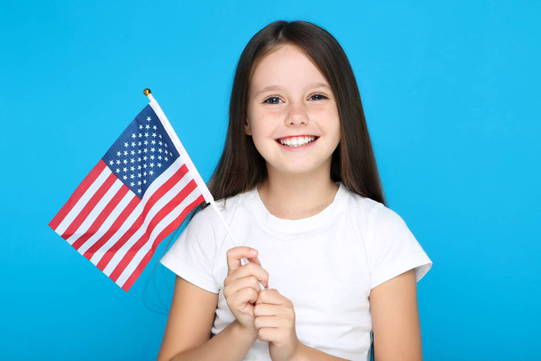 Young girl holding american flag on blue background - Fotó, kép