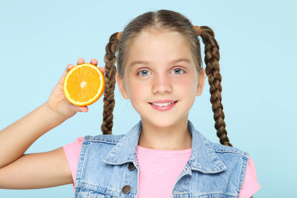 青の背景にオレンジ色の果物を持つ少女 - 写真・画像