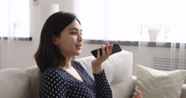 Pretty asian woman holding smartphone uses loudspeaker speaks with boyfriend - Filmagem, Vídeo