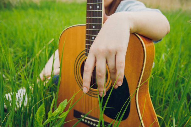 acoustic guitar female hand country music outdoor art concept photography in garden space with green grass summer day time - Fotó, kép