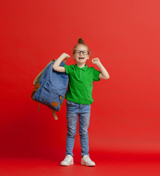 Back to school and happy time! Cute industrious child on color paper wall background. Kid with backpack. Girl ready to study. - Fotografie, Obrázek