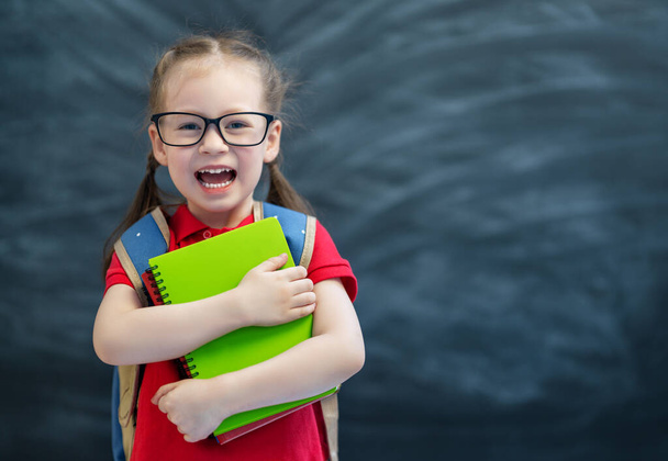 Back to school! Happy cute industrious child is learning in class on background of blackboard. - Zdjęcie, obraz