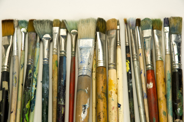 Well used artists paintbrushes on a white paper background - Photo, Image