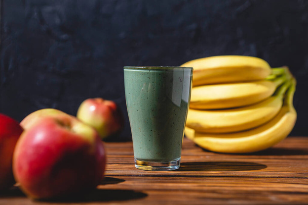 The concept of food and drink, diet and nutrition. Healthy green vegan smoothie with banana, spirulina and ripe apple for summer detoxification - Foto, immagini