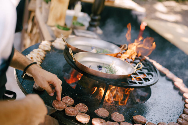 Le chef grille des boulettes de viande pour les mini-hamburgers sur le gril. - Photo, image