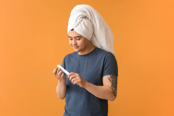 Funny Asian man doing manicure on color background - Fotografie, Obrázek