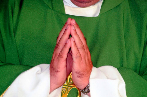 ksiądz w zielonym i białym ubraniu składający ręce na modlitwę - Zdjęcie, obraz