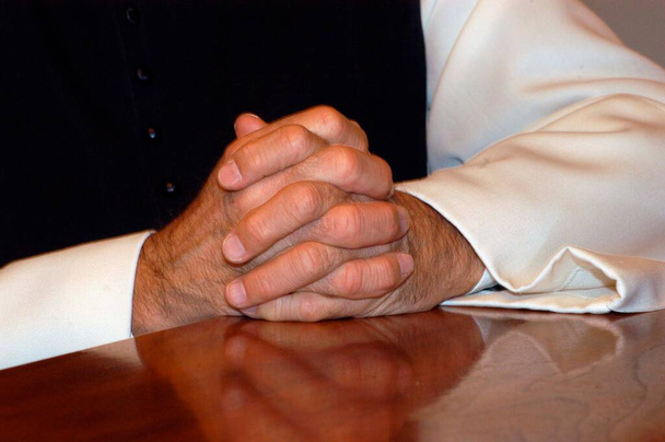 priester in zwart-wit kleding vouwen zijn handen voor het gebed - Foto, afbeelding