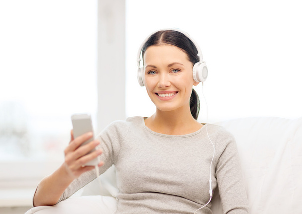 Woman with smartphone and headphones at home - Foto, Imagen