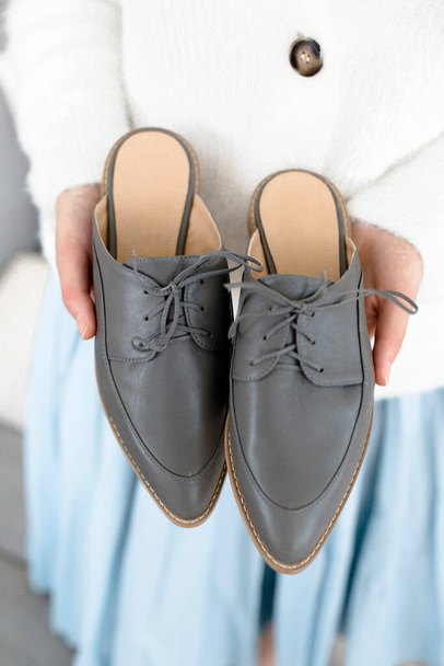 gray stylish and modern women's loafers on a layout, in the hands of a girl, shoes on toes, trendy photos of shoes - Fotoğraf, Görsel