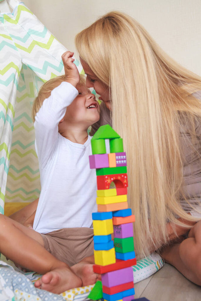 Mom and son build a tower together from the constructor - Foto, afbeelding