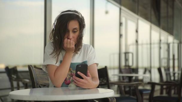 Mujer joven en auriculares mirando el teléfono inteligente
 - Foto, Imagen