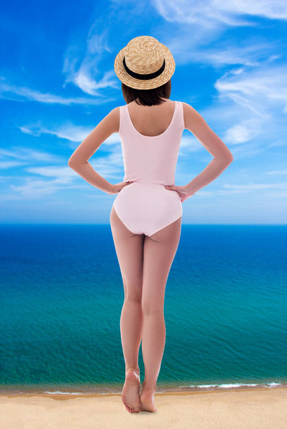 Yaz tatili ve seyahat konsepti - deniz kıyısında duran pembe mayo ve hasır şapkalı dev genç kadının geriye bakışı - Fotoğraf, Görsel