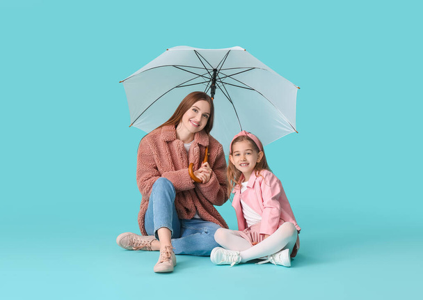 Mother and little daughter with umbrella on color background - Foto, Imagem