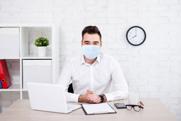 coronavirus, pandemic, quarantine, health care and office work concept - handsome businessman in protective medical mask sitting in office or working at home - Foto, afbeelding