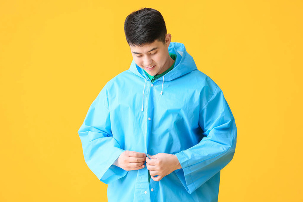 Joven asiático hombre en impermeable en color fondo
 - Foto, Imagen