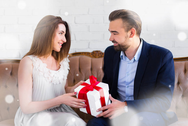 love and holiday concept - handsome man giving gift box to his girlfriend and falling snow - Φωτογραφία, εικόνα