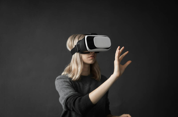Young woman wearing virtual reality goggles headset, vr box. Connection, technology, new generation, progress concept. Girl trying to touch objects in virtual reality. - Foto, Imagen