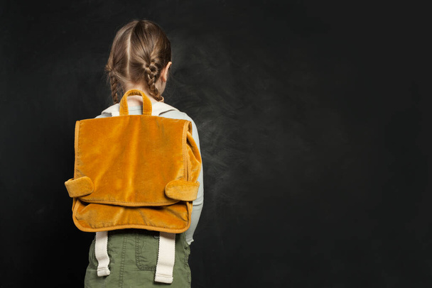 School child girl back with backpack on blackboard background - Фото, зображення