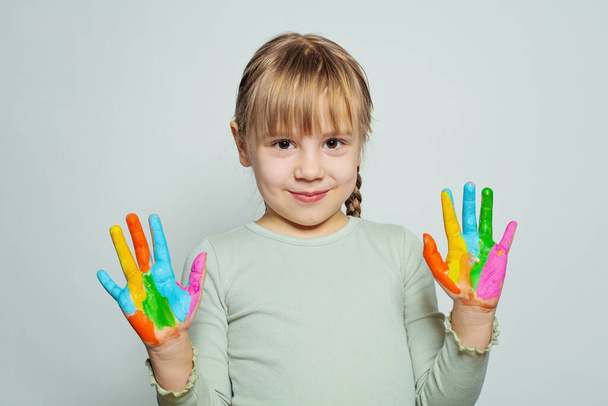 Adorable happy child girl art school student showing her colorful painted hands on white. Girl drawing - Fotoğraf, Görsel