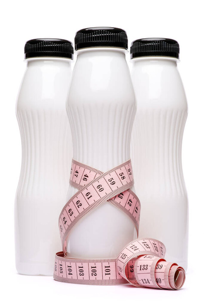 bouteille en plastique blanc blanc propre de yaourt ou de lait et ruban à mesurer isolé sur fond blanc avec chemin de coupe - Photo, image