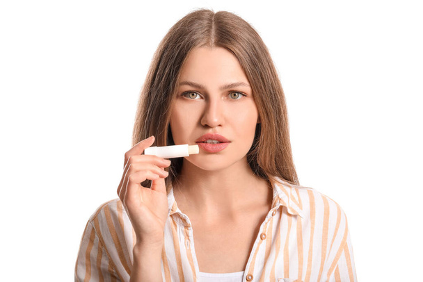 Όμορφη νεαρή γυναίκα με lip balm σε λευκό φόντο - Φωτογραφία, εικόνα