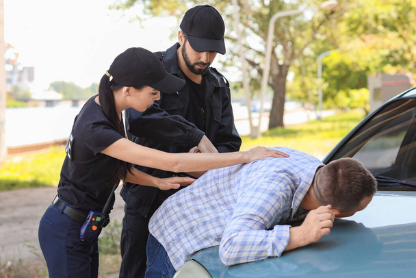 Police officers arresting criminal outdoors - Foto, afbeelding