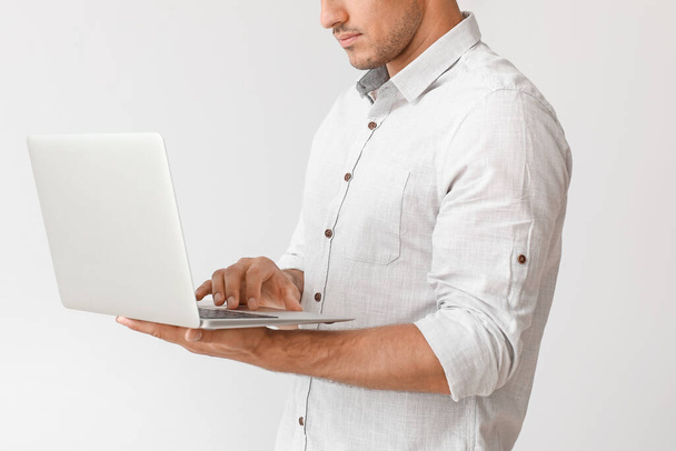 Young businessman in stylish shirt and with laptop on light background - Photo, image